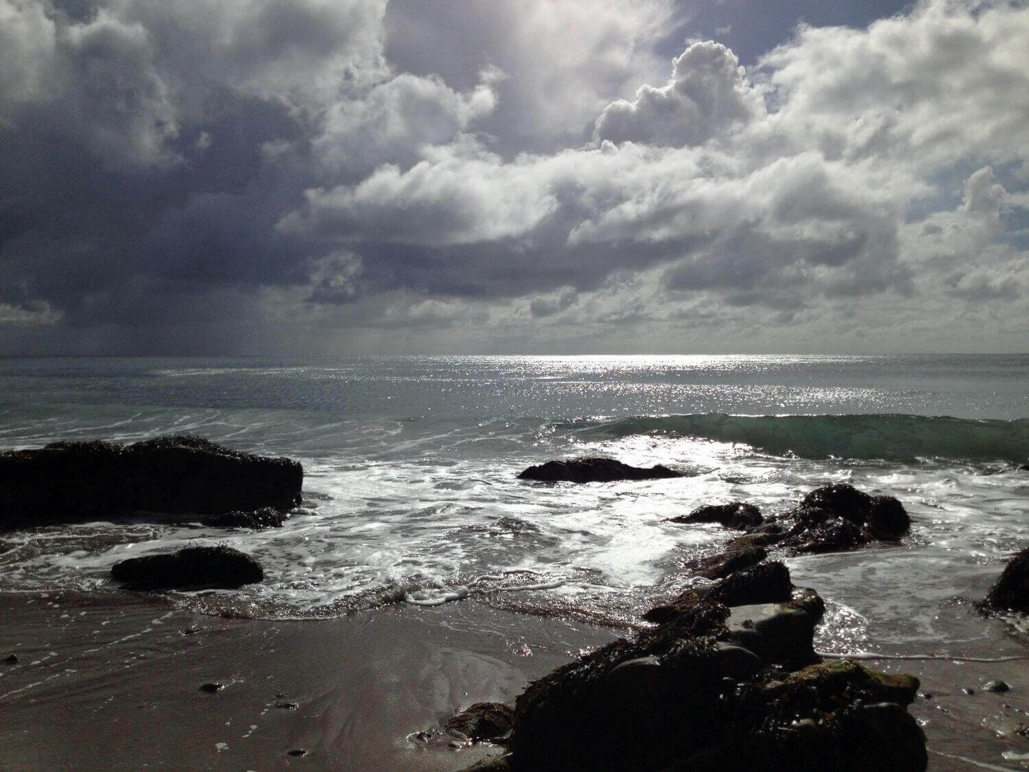 Clouds over the sea with wet sand and rocks